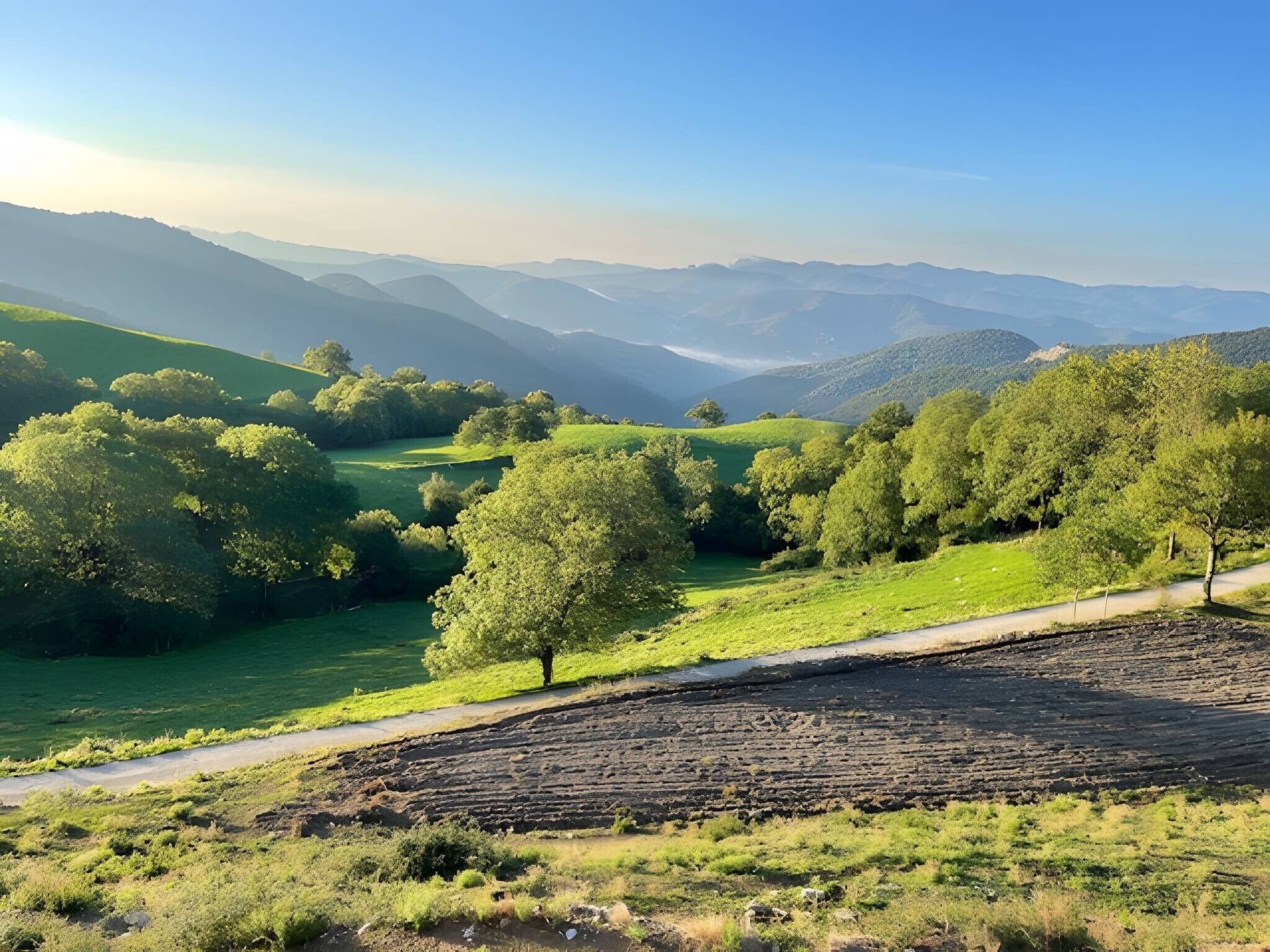 Paisaje rural con colinas onduladas, un río y una carretera.