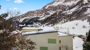 Un paysage montagneux avec des sommets enneigés et, au premier plan, un bâtiment doté d’un toit plat.