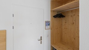 Une porte blanche avec une poignée en métal, une armoire en bois avec un porte-manteau, et une pancarte avec du texte relatif au ski.