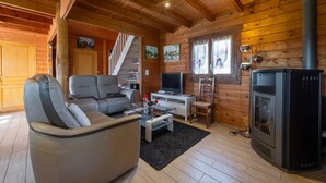 Un interior de madera con sofá, televisión, chimenea y escalera.