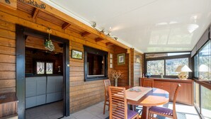 Un interior de madera con comedor, cocina y un amplio ventanal que ofrece vistas.
