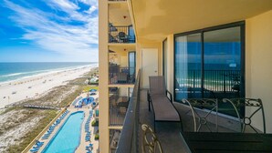 Een balkon met uitzicht op het strand en de oceaan, een zwembad en terrasmeubels.