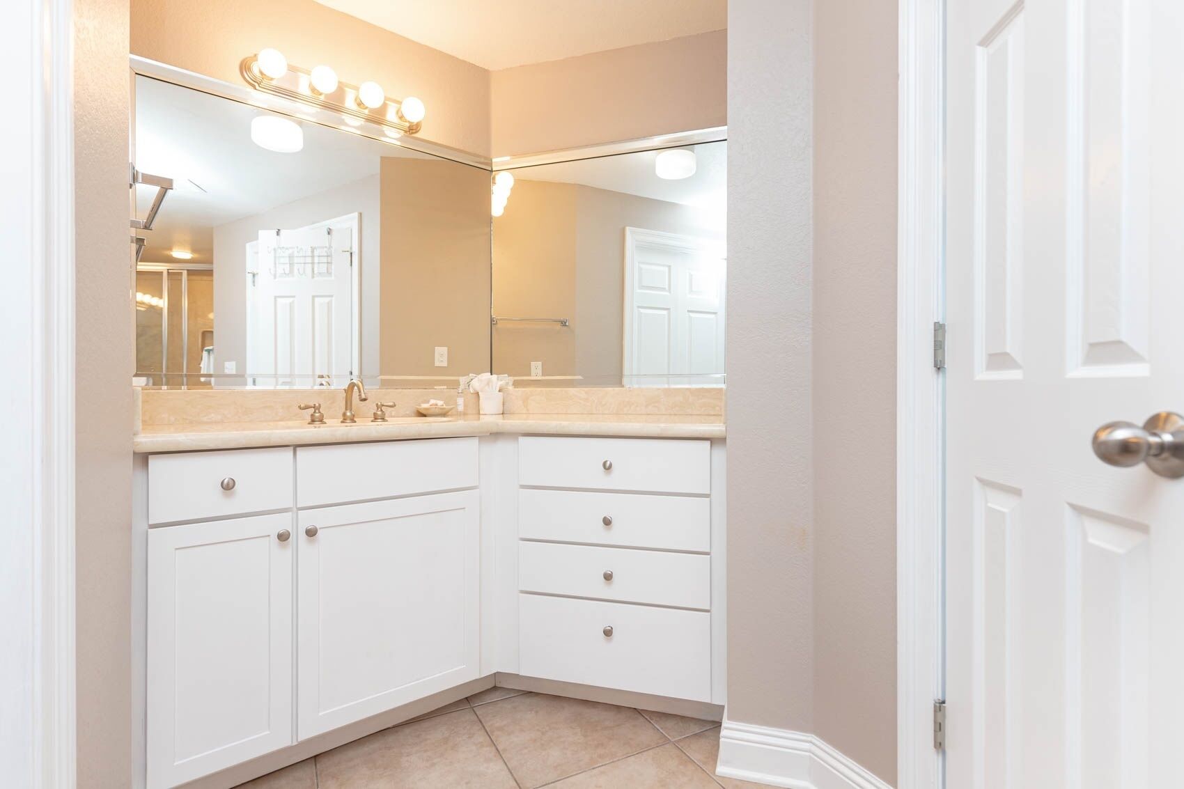 Une salle de bain avec un meuble-lavabo, un miroir avec éclairage intégré et une porte.