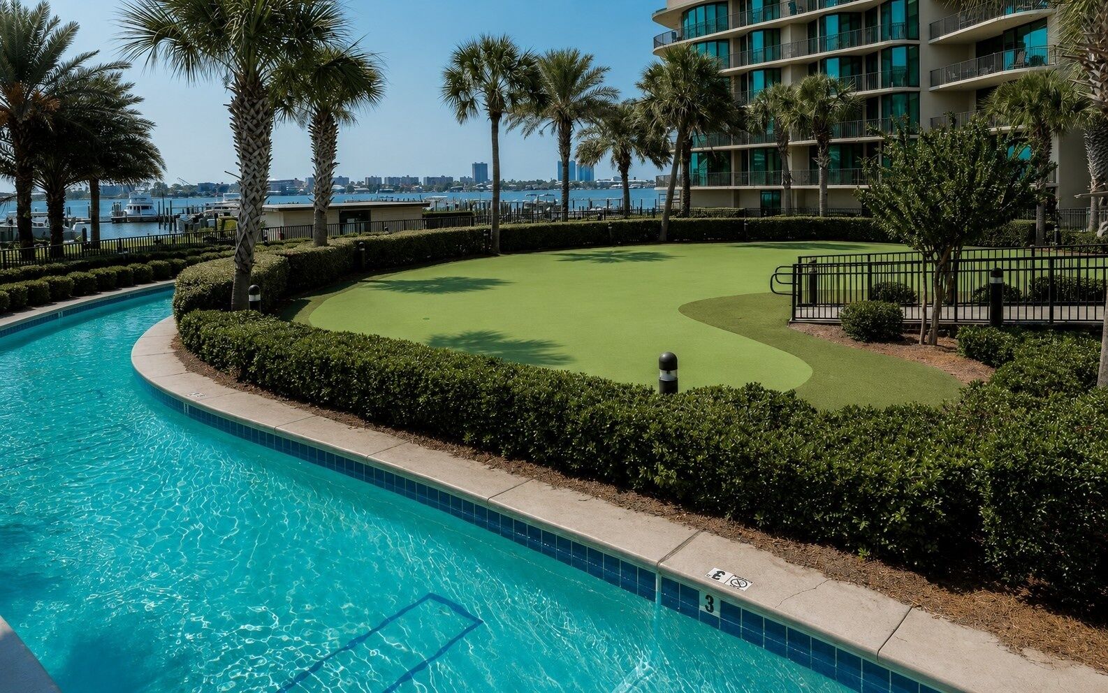 A swimming pool, a golf course, and a building with balconies.
