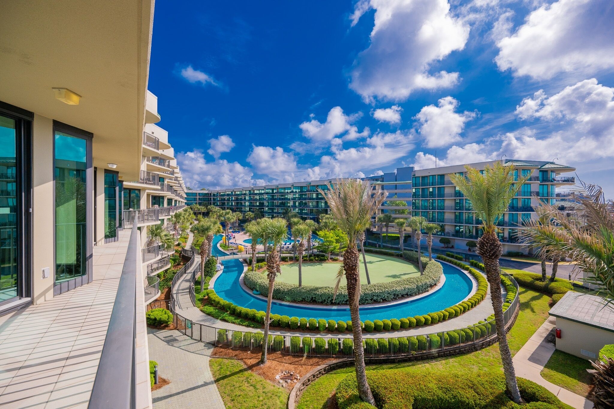 A resort with a pool, palm trees, and modern buildings.