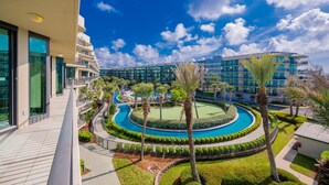 A resort with a pool, palm trees, and modern buildings. - Phoenix On The Bay 1303 3 Bedroom Condo (Orange Beach)