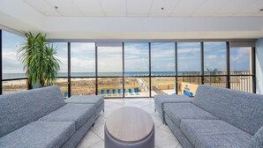 Un balcón con vista a la playa, sofás tapizados en gris y una mesa redonda.