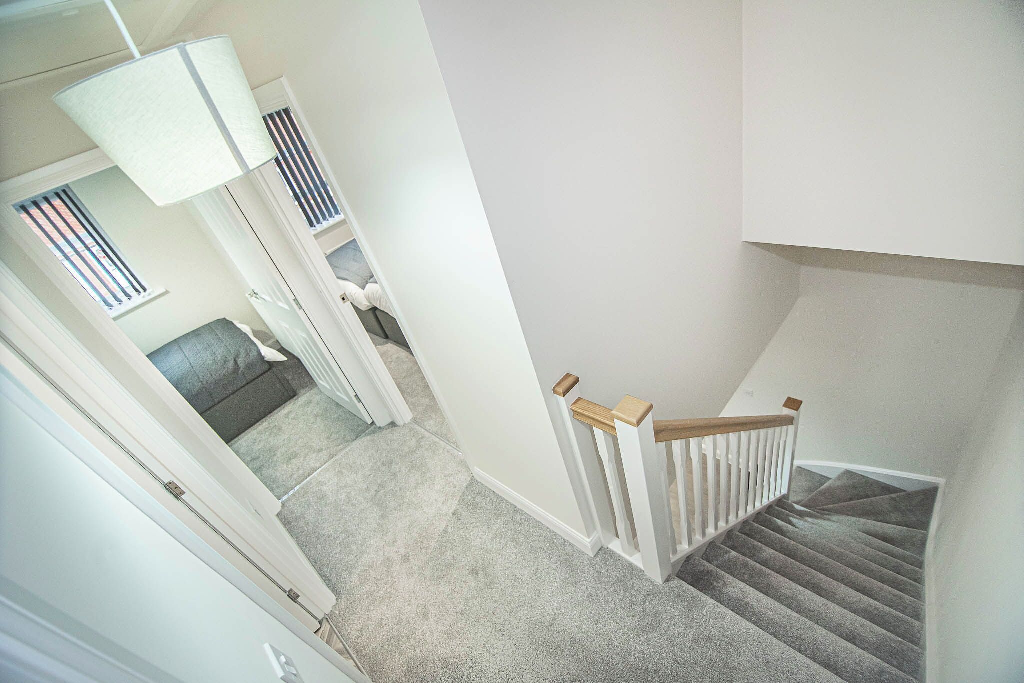 Eine Treppe mit Holzgeländer, Teppichstufen und einer weißen Wand.