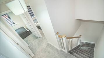 Eine Treppe mit Holzgeländer, Teppichstufen und einer weißen Wand.