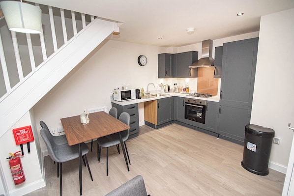 A compact kitchen with a dining area, a staircase, and a fire extinguisher.