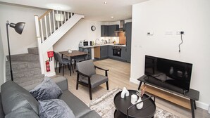 Un salon moderne avec un canapé, un téléviseur et un coin repas.