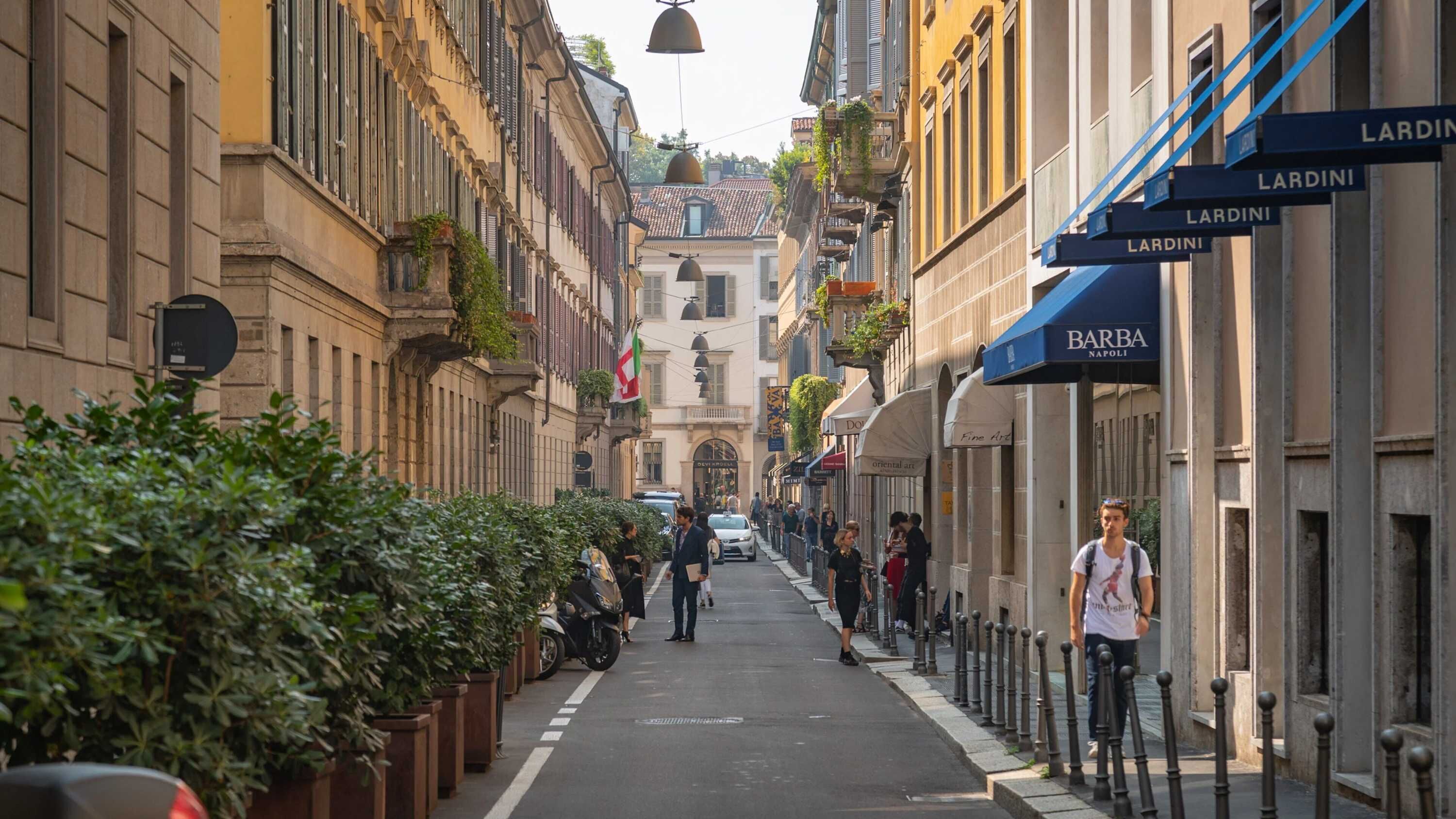 Eine schmale Straße gesäumt von historischen Gebäuden, eine Bar namens 'Barba Napoli' und ein Schild für 'LARDINI'.
