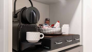 Eine Kaffeemaschine mit Tasse auf einem Tablett, eine Schüssel und ein Schrank mit Schubladen.