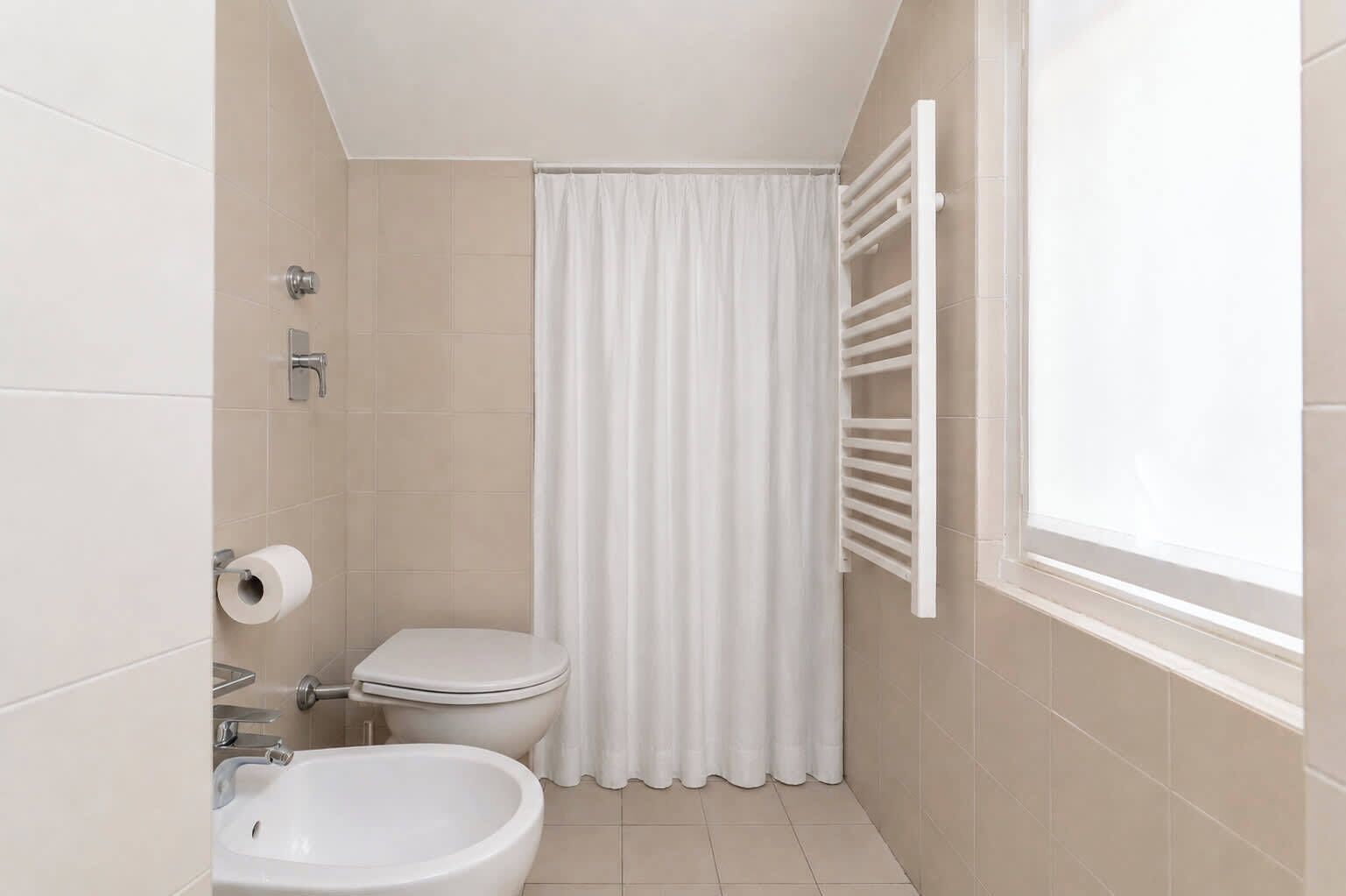 Ein kleines Badezimmer mit Toilette, Bidet und Duschvorhang.