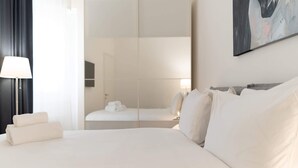 Et hotelværelse med en stor seng, et natbord, en lampe og et billede på væggen.