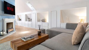 Un salon moderne avec une cheminée, un téléviseur à écran plat, un canapé, une table basse et une lampe.