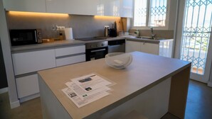 A modern kitchen with white cabinets, a microwave, a coffee machine, and a sink. - Green Hill Recreational Luxury (Iraklio)