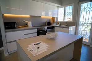 A modern kitchen with white cabinets, a microwave, a coffee machine, and a sink.