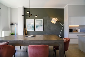 Een moderne eethoek met een houten tafel, rode stoelen en moderne verlichtingsarmaturen.