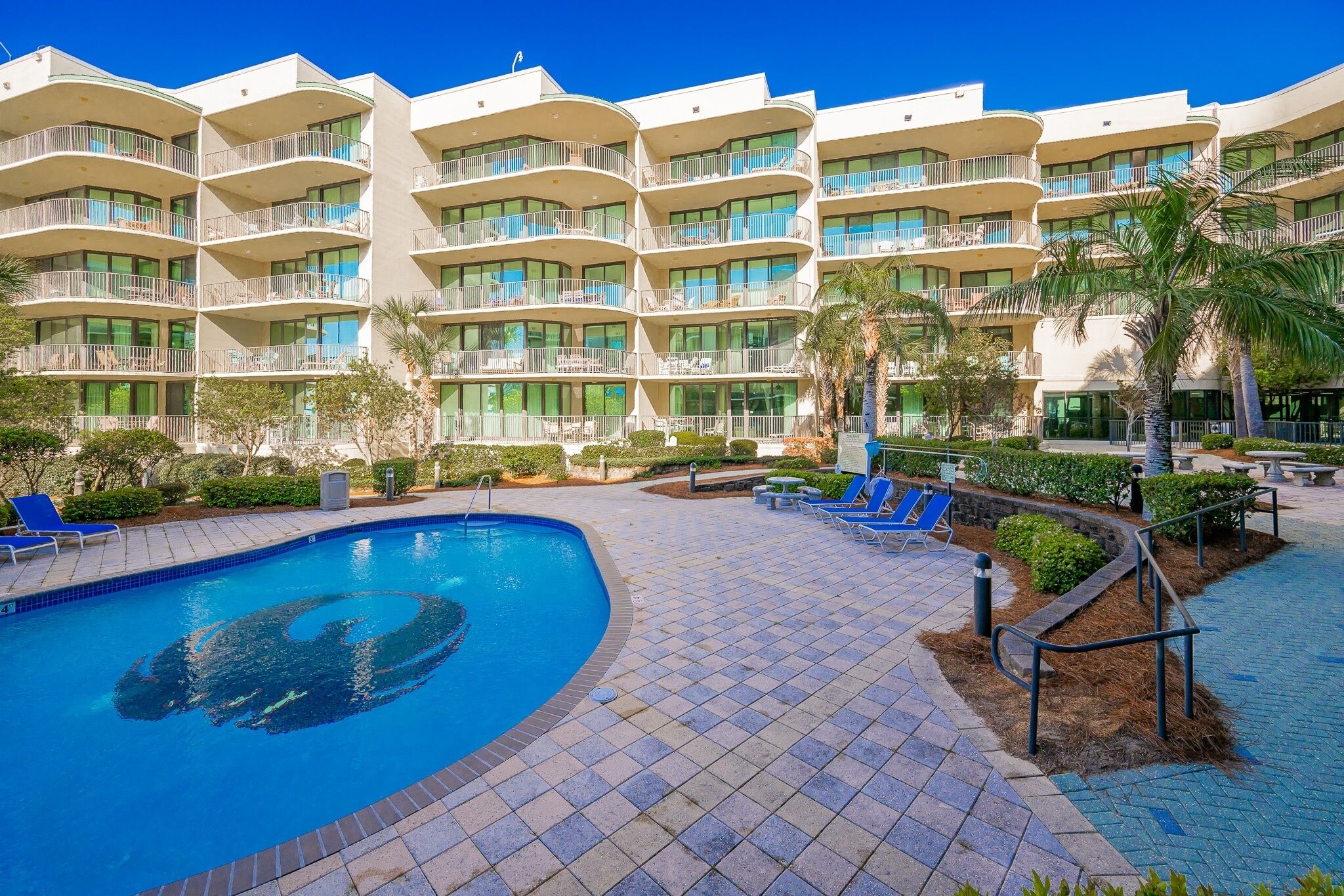 A hotel with a swimming pool, multiple balconies, and outdoor seating areas.