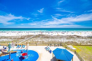 Un resort en la playa con zona de piscina, sillas de descanso y vista al océano.