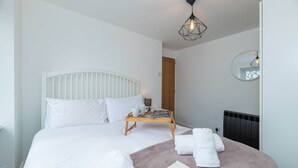 Une chambre d’hôtel avec un lit, une table de chevet avec un plateau, un miroir et un radiateur.