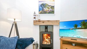 Un salon avec une cheminée, un téléviseur et un canapé.