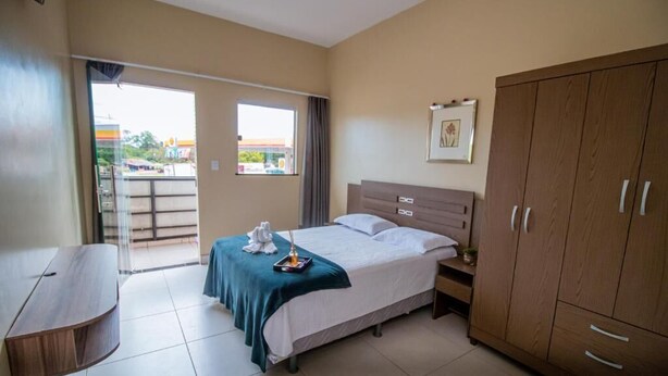 Habitación de hotel con cama, armario de madera, escritorio y vistas por la ventana.