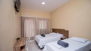 Habitación de hotel con dos camas, un escritorio, un televisor y una ventana con cortinas.