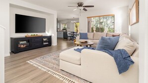 Ein Wohnzimmer mit einer Couch, einem Fernseher und einem Deckenventilator.