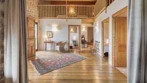 Une pièce spacieuse avec un plancher en bois, une grande moquette, un escalier et un balcon.