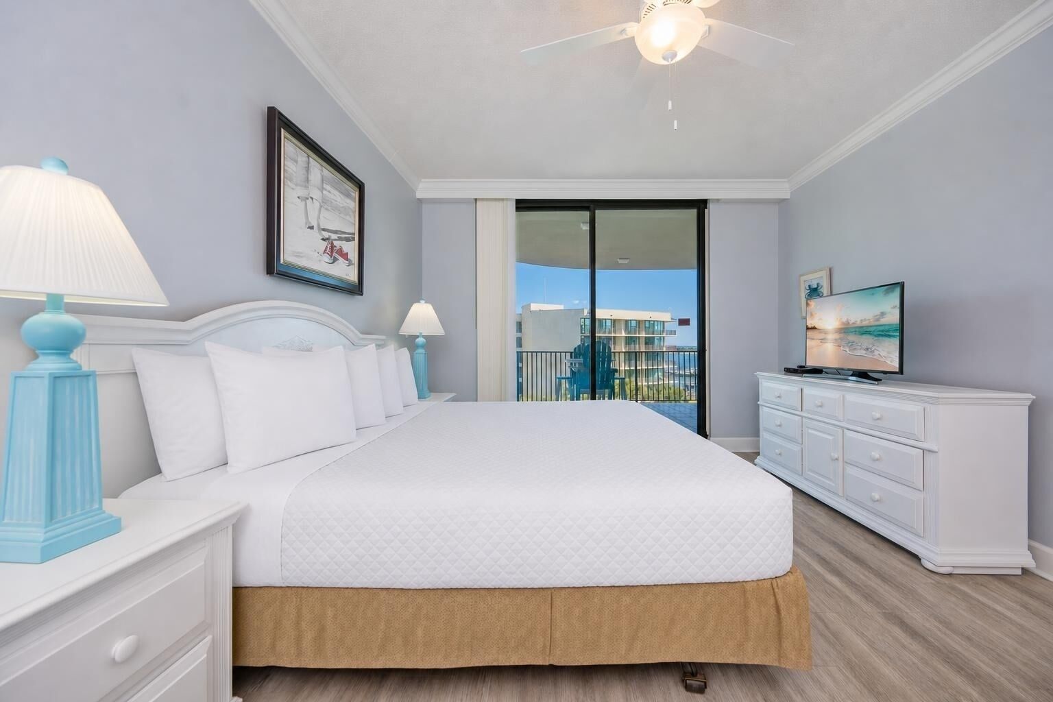 Ein Hotelzimmer mit Bett, Fernseher, Balkon mit Blick und Deckenventilator.
