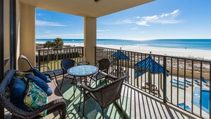 A balcony with wicker furniture, a small table, and a view of the beach and ocean. - Phoenix V 213 2 Bedroom Condo (Orange Beach)