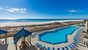 A pool with lounge chairs, a beach view, and a clear sky. - Phoenix V 213 2 Bedroom Condo (Orange Beach)