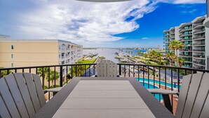A balcony with a view of a marina, a pool, and surrounding buildings. - Lighthouse On The Bay 2413 3 Bedroom Condo (Orange Beach)