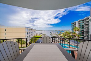 Ein Balkon mit Blick auf einen Hafen, ein Schwimmbecken und umliegende Gebäude.