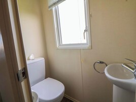 Un baño pequeño con inodoro, lavamanos y ventana.