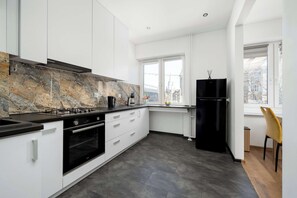 Eine moderne Küche mit weißen Schränken, einem schwarzen Kühlschrank, einem Herd und einem Fenster mit Blick.
