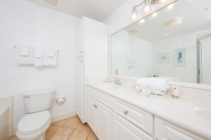 Un baño con inodoro, lavamanos con espejo y un perchero para toallas.