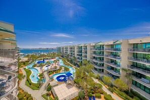 Un resort con edificios de varios pisos, una zona de piscina y vista al mar.