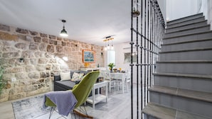 Un salon moderne avec un mur en pierre, un fauteuil à bascule vert, un coin repas et un escalier.
