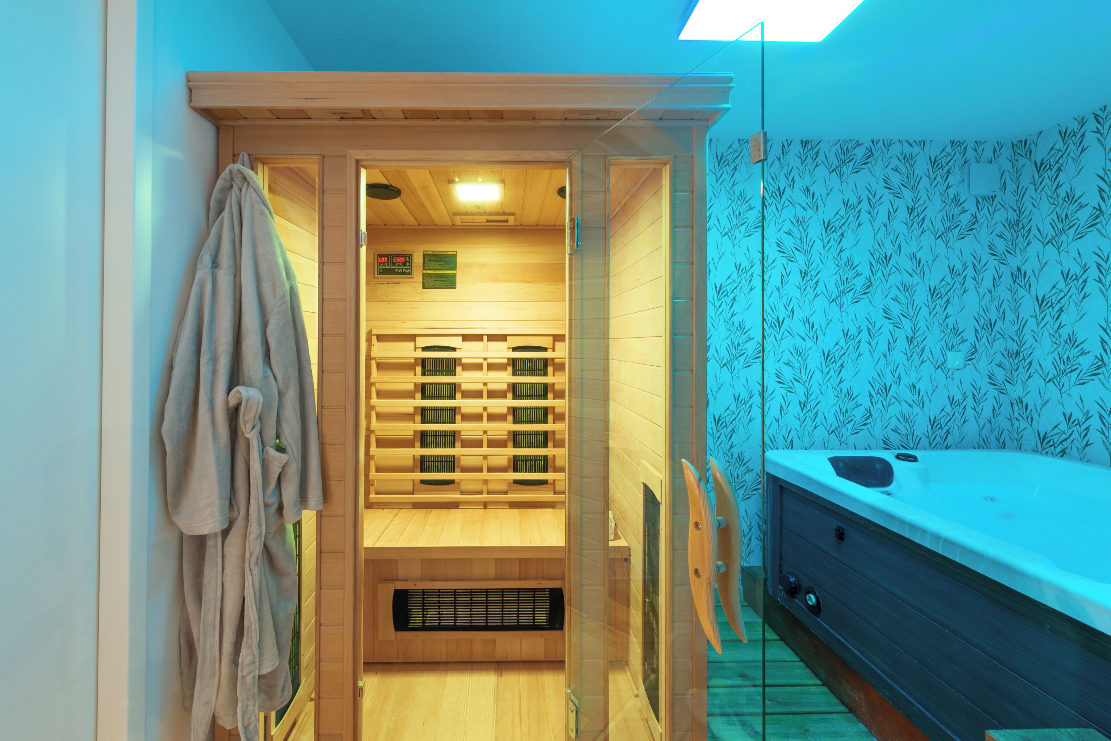 A sauna room with a wooden bench, a towel rack, and a hot tub.