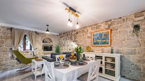 Un coin repas agrémenté d’un mur en pierre, d’un tableau et d’une table à manger entourée de chaises et d’un canapé.