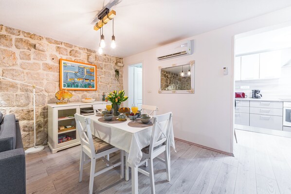 Un coin repas avec un mur en pierre, un tableau et, au fond, une cuisine moderne.