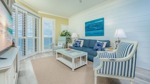 A living room with a sofa, armchair, coffee table, and a painting on the wall. - Phoenix V 1209 2 Bedroom Condo (Orange Beach)