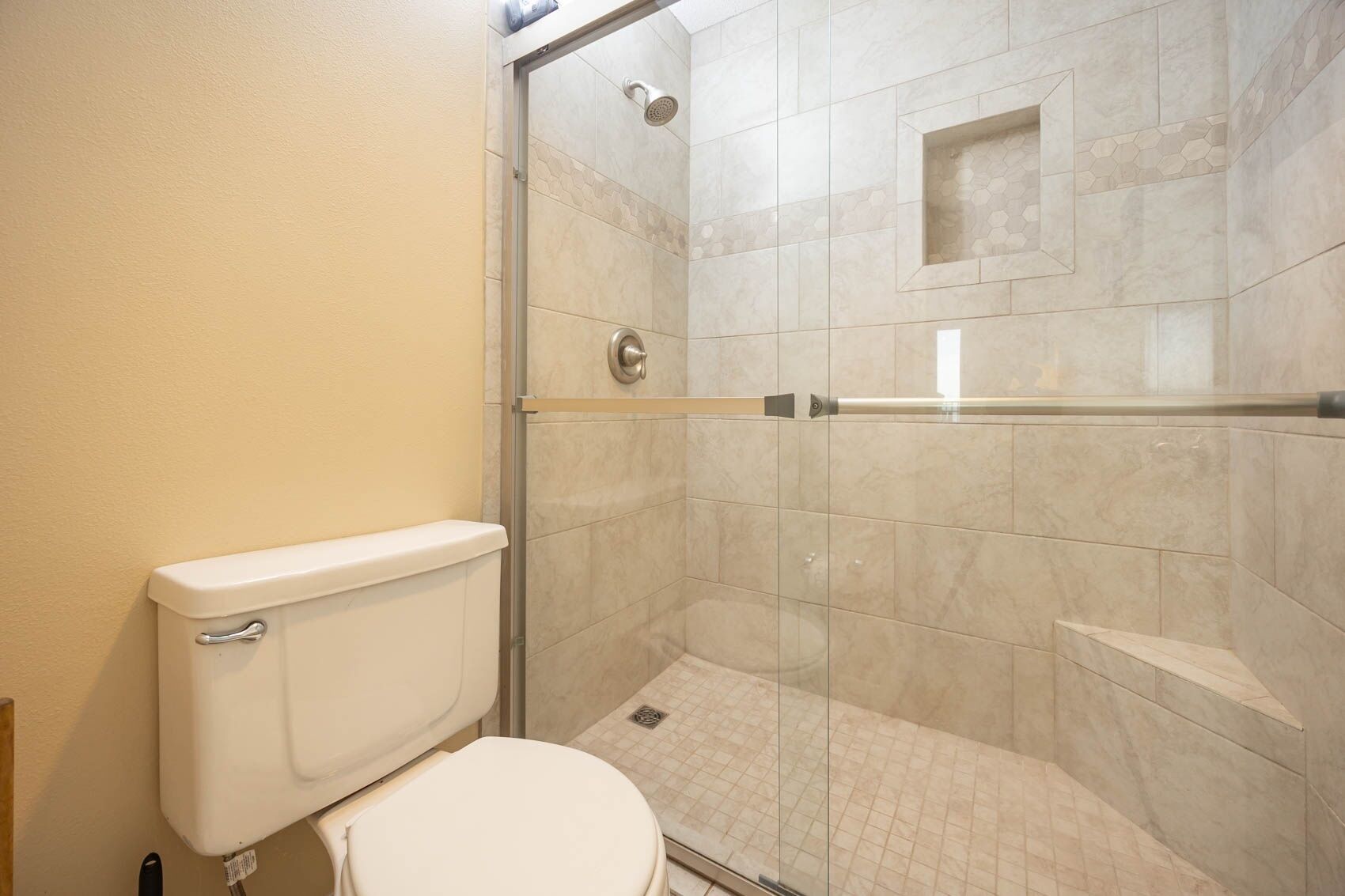 Une salle de bain avec des toilettes, une douche et une porte en verre.