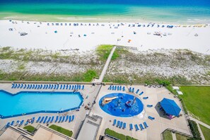 An aerial view of a beach resort with a swimming pool, sun loungers, and beach umbrellas. - Phoenix V 1106 2 Bedroom Condo (Orange Beach)