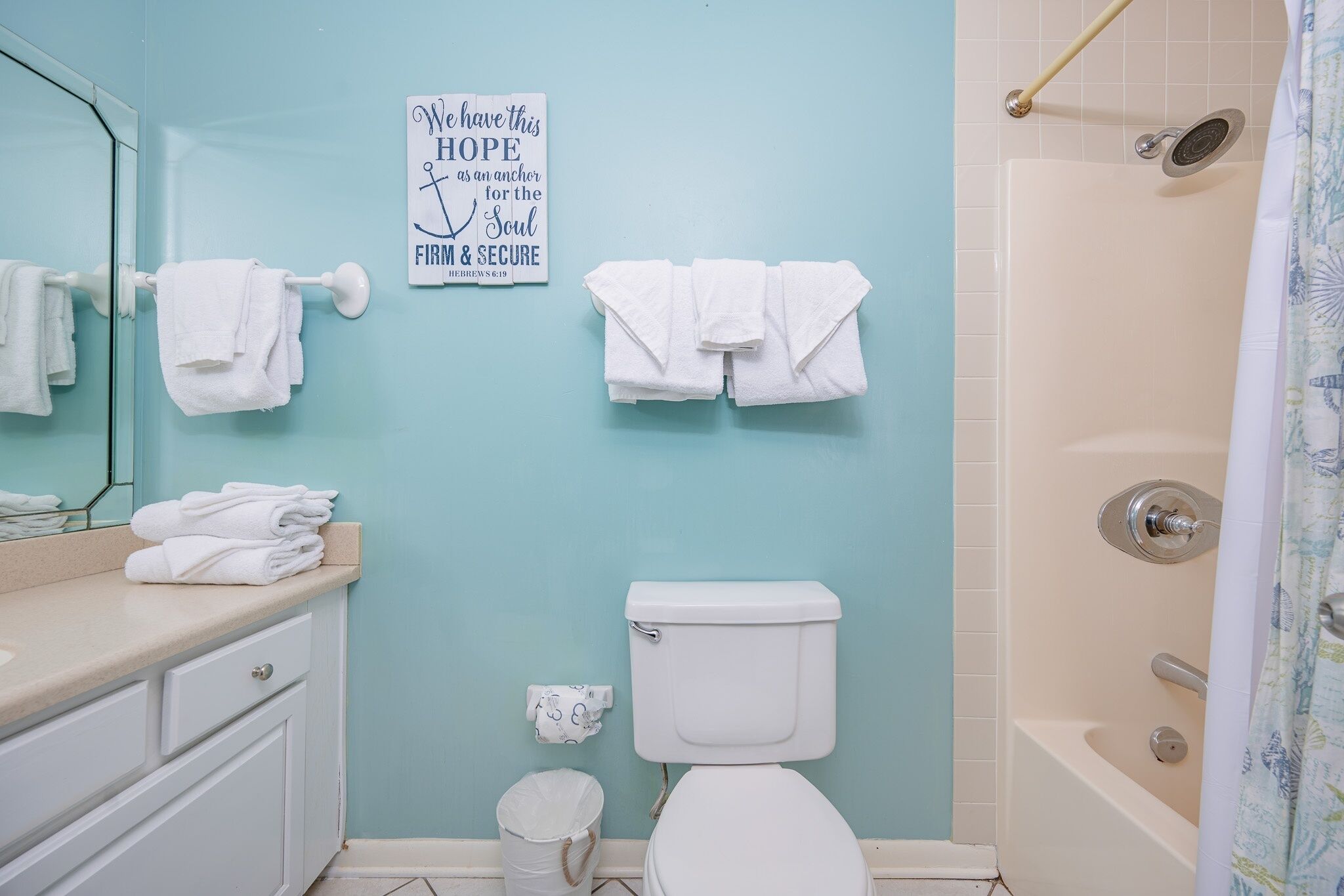Un baño con inodoro, lavamanos, toallero y cortina de ducha.