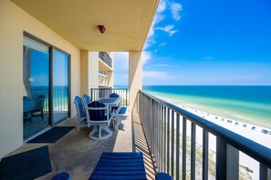 A balcony with a table and chairs, a view of the beach, and a clear sky. - Phoenix V 1106 2 Bedroom Condo (Orange Beach)