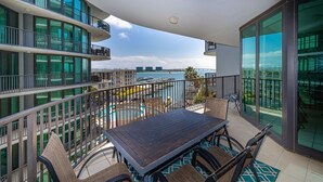 Ein Balkon mit Tisch und Stühlen mit Blick auf einen Hafen und Gebäude.
